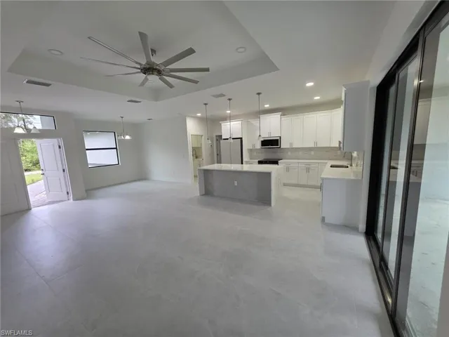 Kitchen featuring a kitchen island, white cabinets, light countertops, freestanding refrigerator, and a tray ceiling