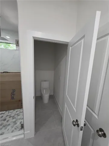 Full bathroom featuring a shower stall, toilet, and baseboards