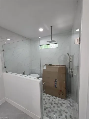 Full bath featuring a shower stall, tile walls, and recessed lighting