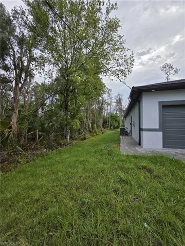 View of yard with an attached garage and central AC unit
