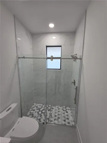 Full bathroom with baseboards, a shower stall, toilet, and recessed lighting