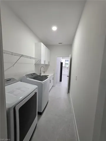Washroom with cabinet space, baseboards, visible vents, washer and dryer, and a sink