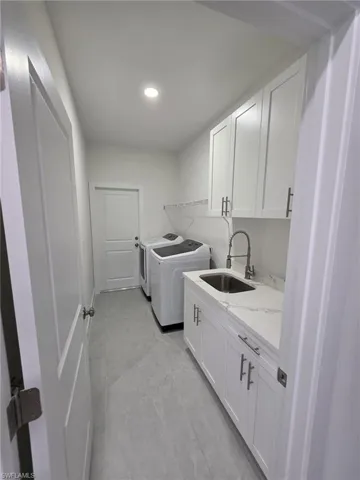 Washroom with washer and clothes dryer, a sink, cabinet space, and recessed lighting