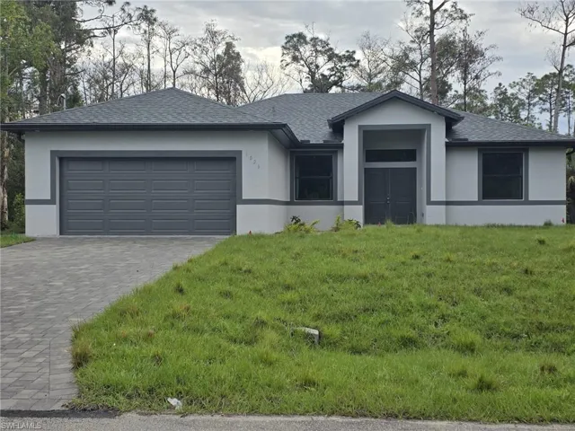 View of front of house with roof with shingles, an attached garage, decorative driveway, a front lawn, and stucco siding
