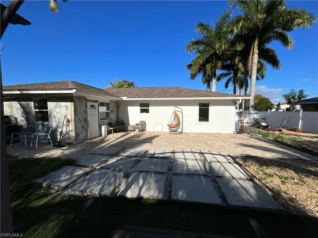 Rear view of property with a patio area, stucco siding, and roof with shingles