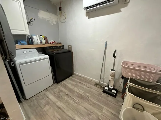 Laundry room with light wood-style flooring, cabinet space, and washing machine and dryer