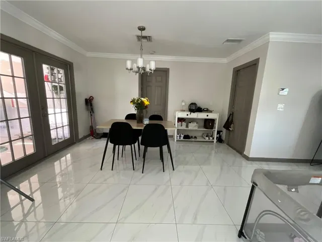 Dining area with ornamental molding, french doors, and suspended lighting