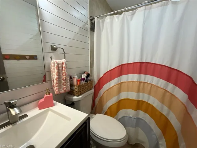 Bathroom with a shower with shower curtain, wood walls, and vanity