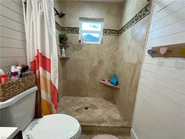 Bathroom featuring wood walls and a shower stall