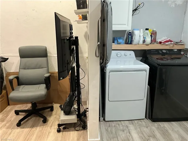 Laundry room with light wood-style floors, separate washer and dryer, cabinet space, and a desk