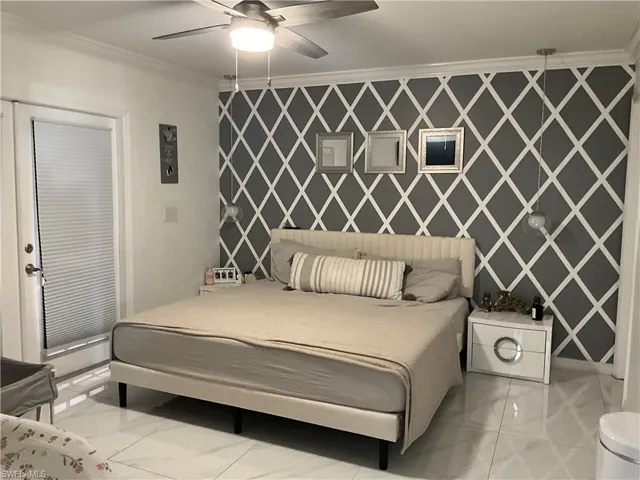 Bedroom with an accent wall, crown molding, wallpapered walls, and a ceiling fan