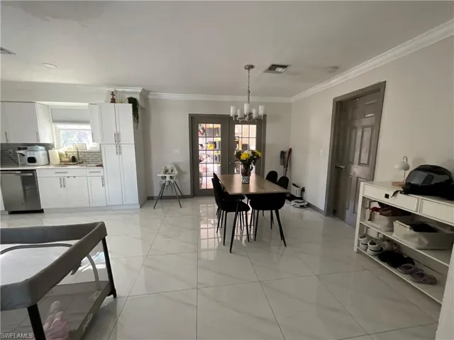 Dining area with suspended lighting and crown molding