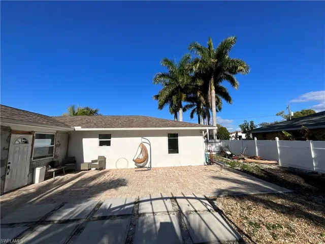 Rear view of house with stucco siding, a patio, a fenced backyard, and roof with shingles