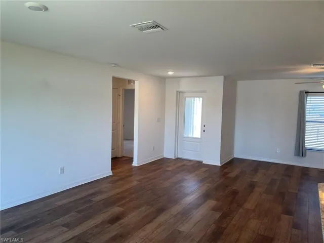 Spare room featuring ceiling fan, a healthy amount of sunlight, and dark hardwood / wood-style floors