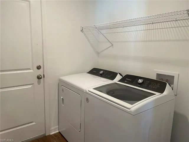 Clothes washing area featuring washing machine and dryer and dark wood-type flooring