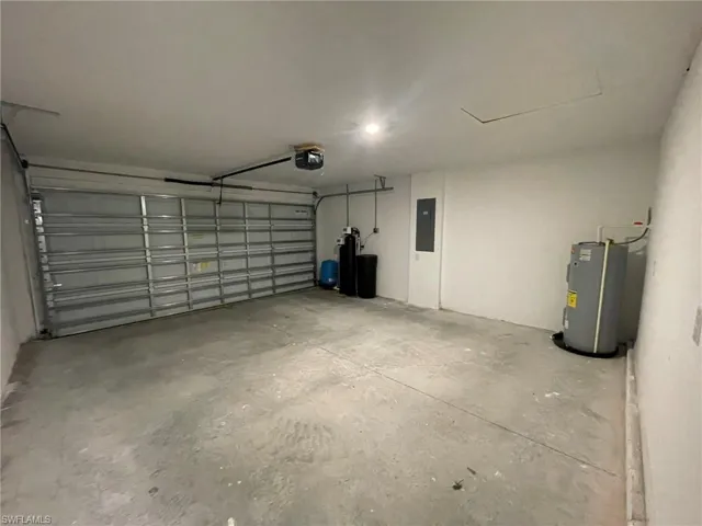 Garage with electric panel, water heater, and a garage door opener