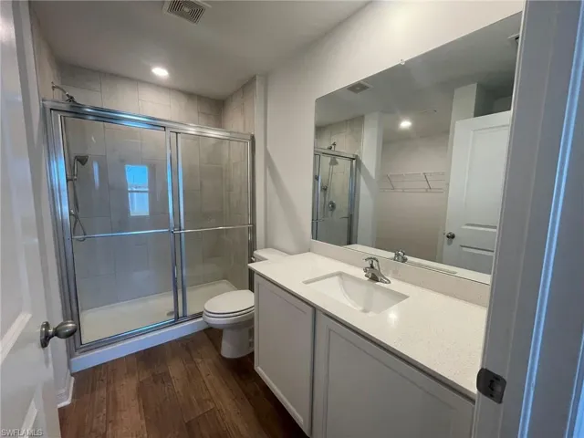 Bathroom with hardwood / wood-style flooring, vanity, toilet, and walk in shower