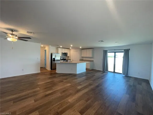 Unfurnished living room featuring dark hardwood / wood-style floors and ceiling fan