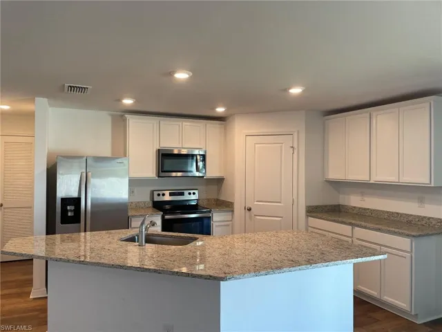 Kitchen featuring a center island with sink, white cabinets, and stainless steel appliances