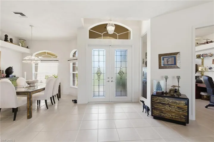 Beautiful Foyer featuring french doors, a chandelier, dining room to the left and den/office to the right.