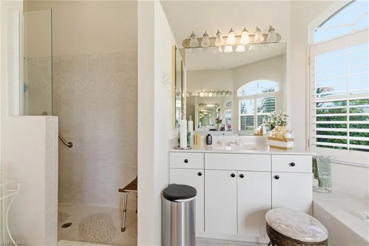 Full bathroom with walk in shower, vanity, and tiled bath