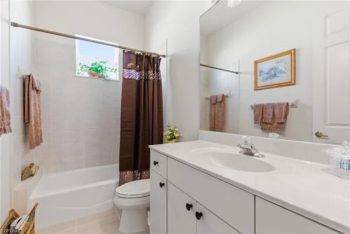 Bathroom with vanity, shower / bath combo with shower curtain, and light tile patterned floors