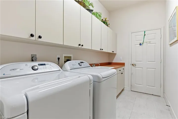 Laundry room with sink, washing machine and dryer and plenty of cabinet space