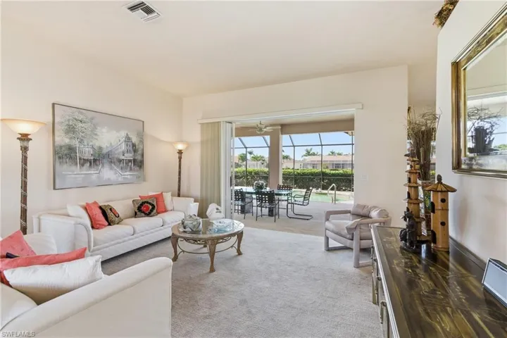 Carpeted living room leading to the lanai and pool