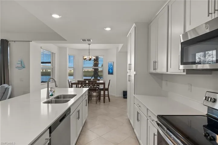 Kitchen featuring stainless steel appliances, sink, hanging light fixtures, and white cabinets