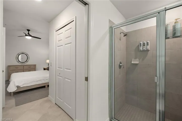 Bathroom with a shower with shower door, tile patterned floors, and ceiling fan