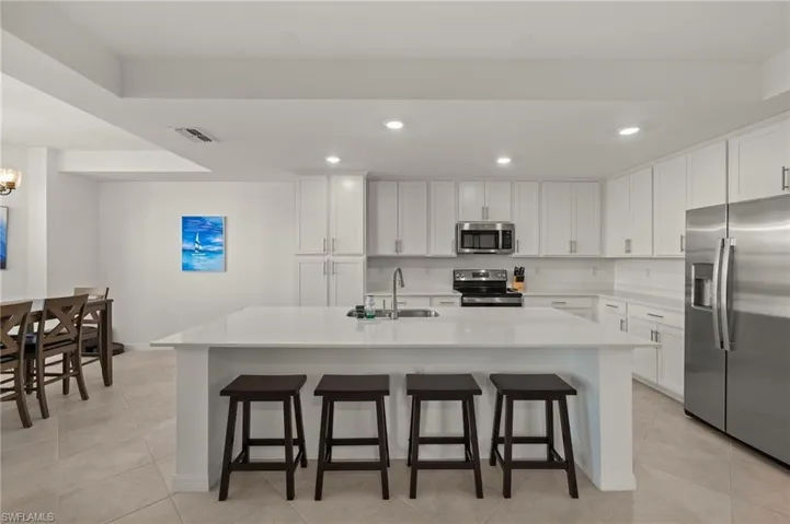 Kitchen with a kitchen island with sink, white cabinetry, and stainless steel appliances