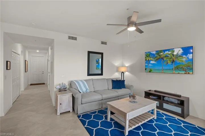 Living room featuring light tile patterned floors and ceiling fan