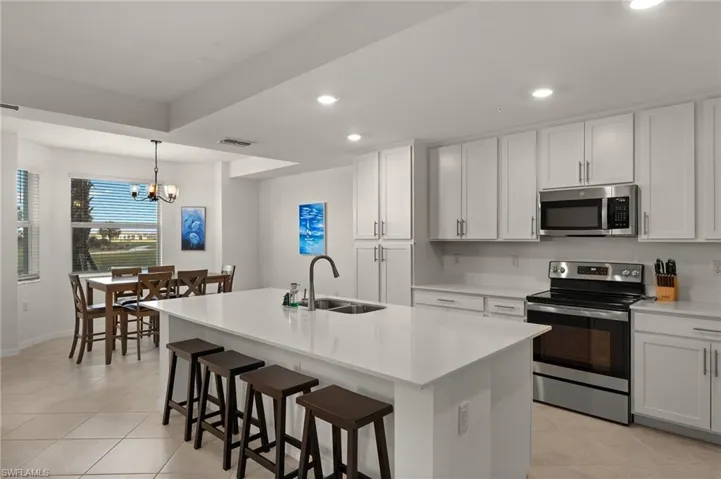 Kitchen featuring white cabinetry, stainless steel appliances, a kitchen island with sink, and sink