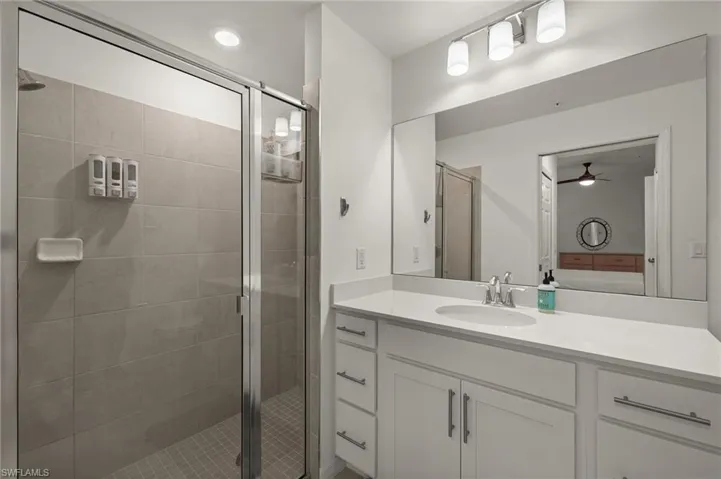 Bathroom with vanity, a shower with door, and ceiling fan