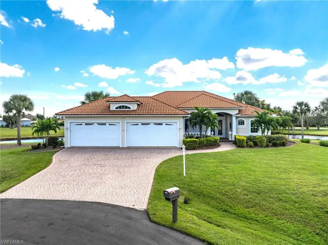 Mediterranean / spanish-style house featuring decorative driveway, a front yard, stucco siding, a tile roof, and a garage