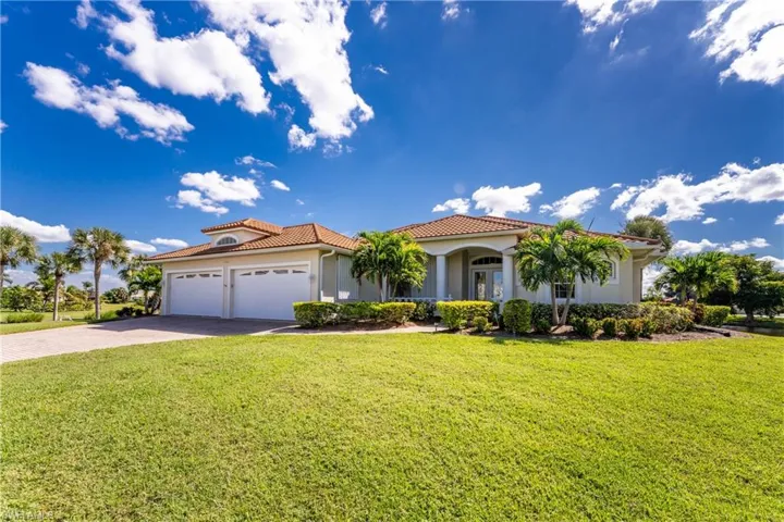Mediterranean / spanish house with a front yard, stucco siding, a tiled roof, a garage, and driveway