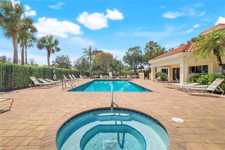 Community pool featuring fence, a patio area, and a hot tub