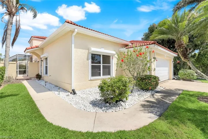 View of property exterior featuring a lawn, a tile roof, concrete driveway, and stucco siding