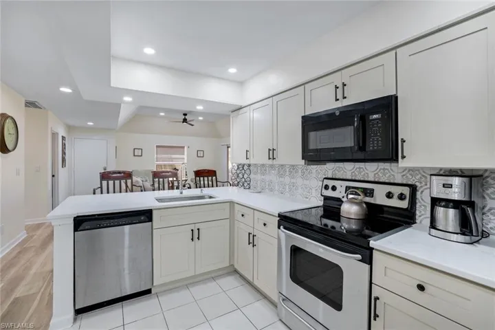 Kitchen with a peninsula, a sink, decorative backsplash, a ceiling fan, and appliances with stainless steel finishes