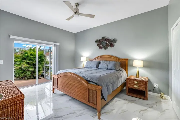 Bedroom with ceiling fan, marble finish floor, baseboards, and access to outside