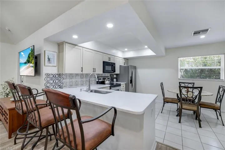 Kitchen featuring stainless steel appliances, light countertops, a sink, baseboards, and tasteful backsplash