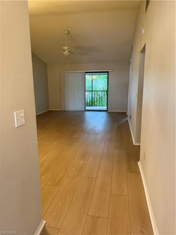 Spare room with light wood-type flooring, lofted ceiling, and a ceiling fan