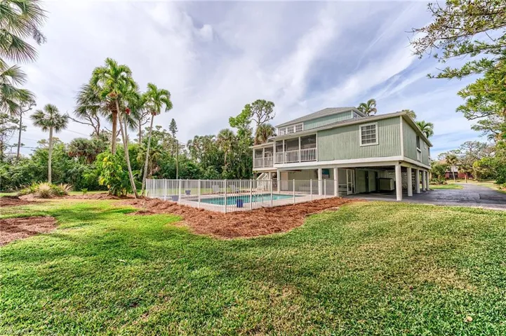 View of pool featuring a lawn and a sunroom