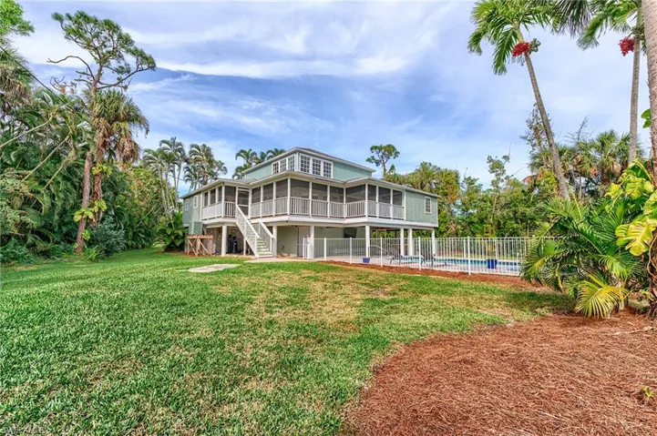 Back of house with a yard, a fenced in pool, and a sunroom