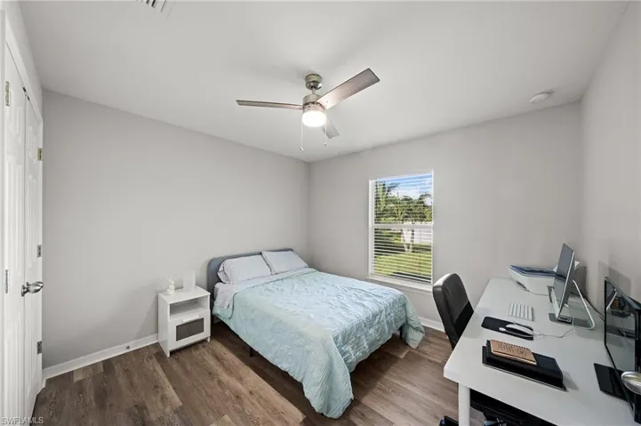 Bedroom with wood finished floors, an office area, and ceiling fan