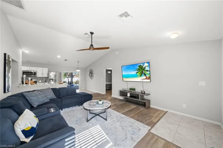Living area with light wood-style flooring, ceiling fan, and high vaulted ceiling