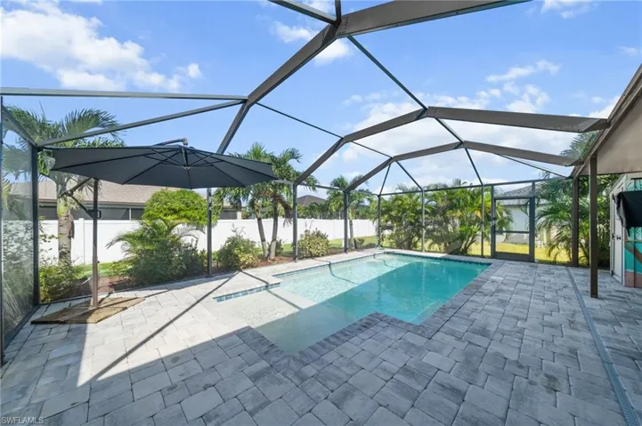Outdoor pool featuring a sunroom, glass enclosure, and a patio area