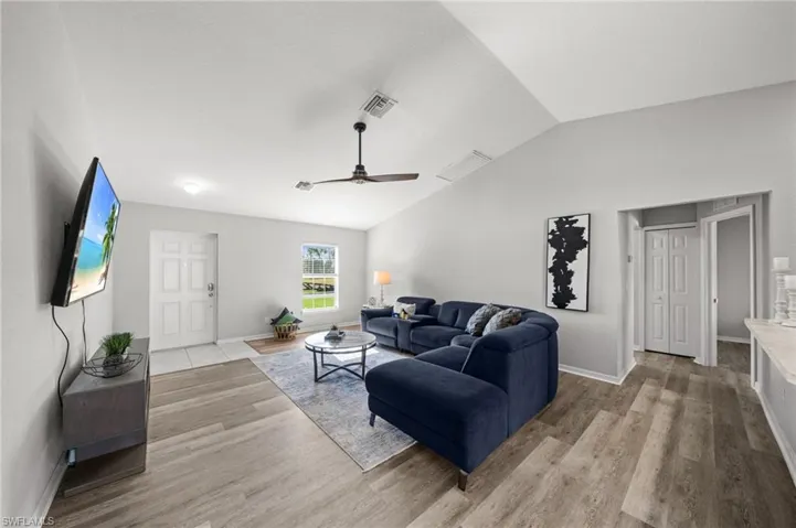 Living area featuring lofted ceiling, a ceiling fan, and light wood finished floors