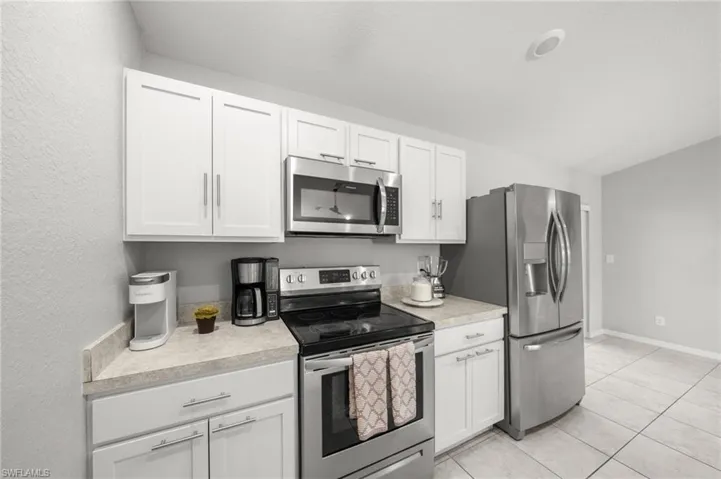 Kitchen featuring stainless steel appliances, light countertops, and white cabinets