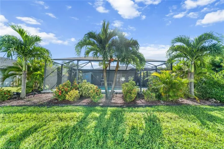 View of green lawn featuring a sunroom and glass enclosure